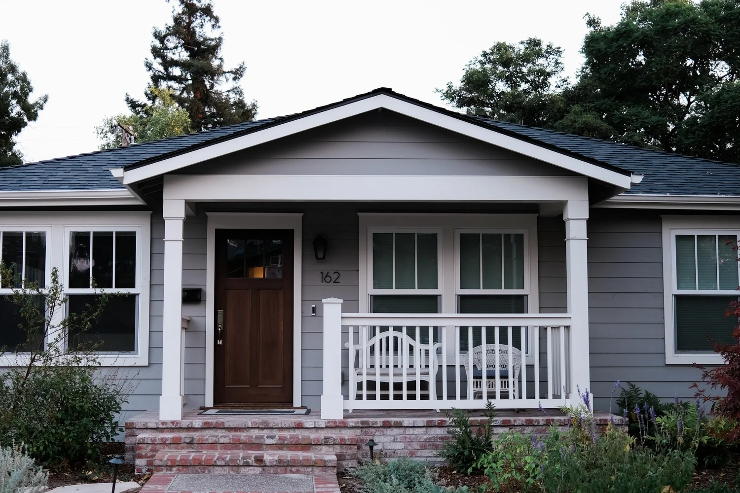 Welcoming home with a covered porch, craftsman details, and garden